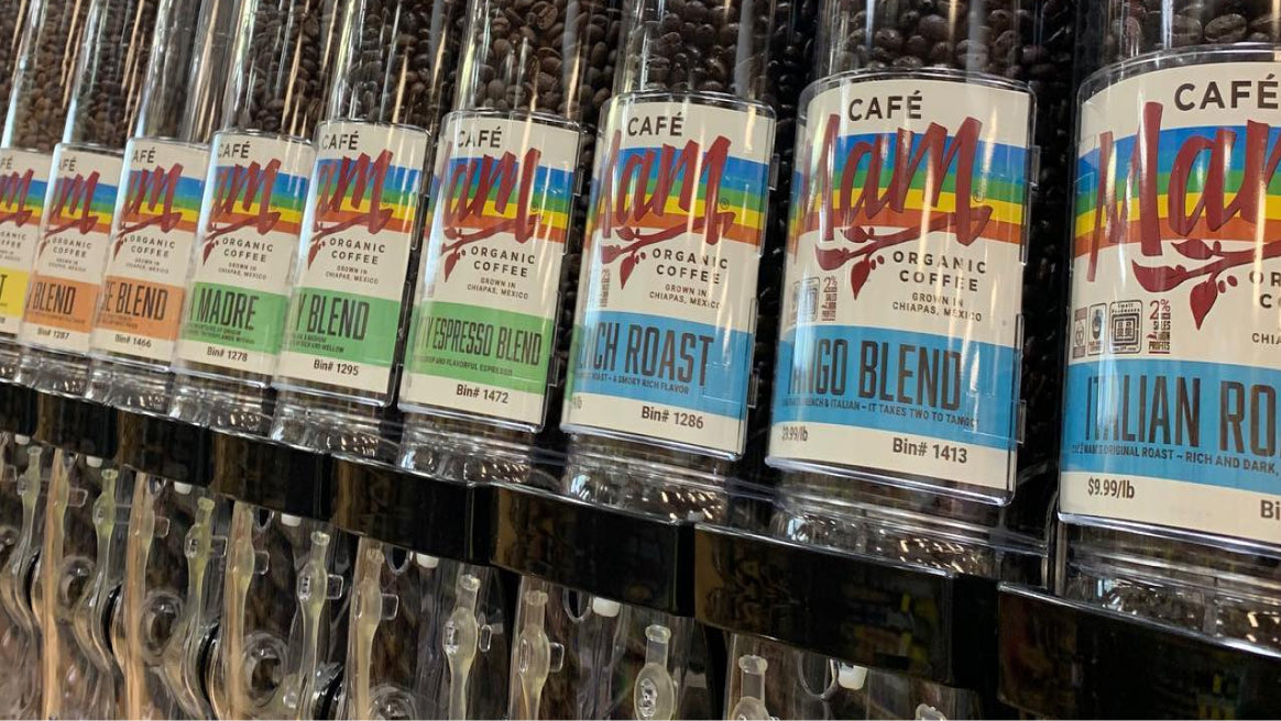 Row of coffee packages with colorful labels on a shelf.