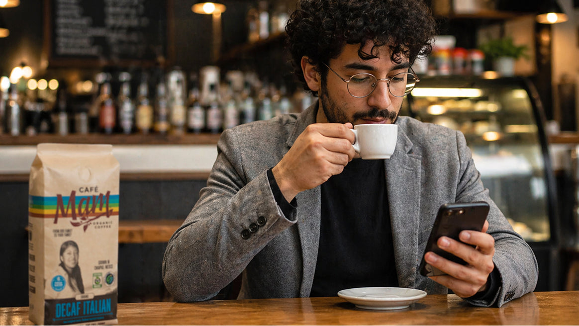 Man drinking coffee and using a phone in a cafe