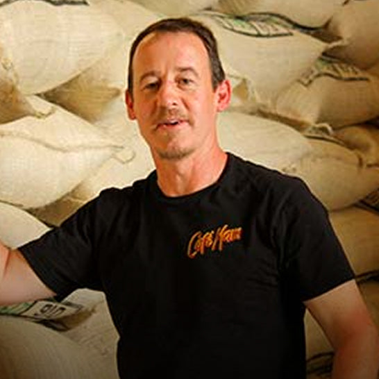 Man wearing a black t-shirt with 'Coffee Bean' logo in front of coffee bags