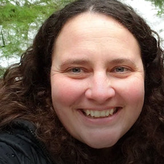 Person with curly hair smiling outdoors