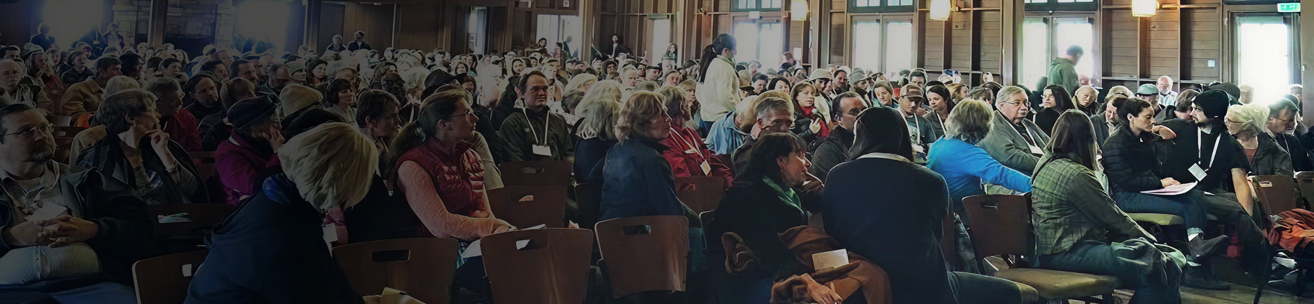 Large indoor gathering of people in a lecture hall or conference room.