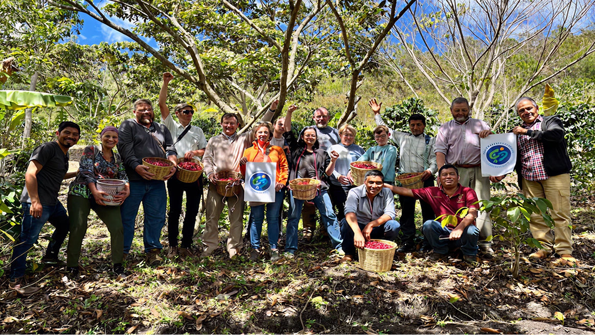 Group of people in a forest holding baskets, with some wearing aprons and a visible logo.